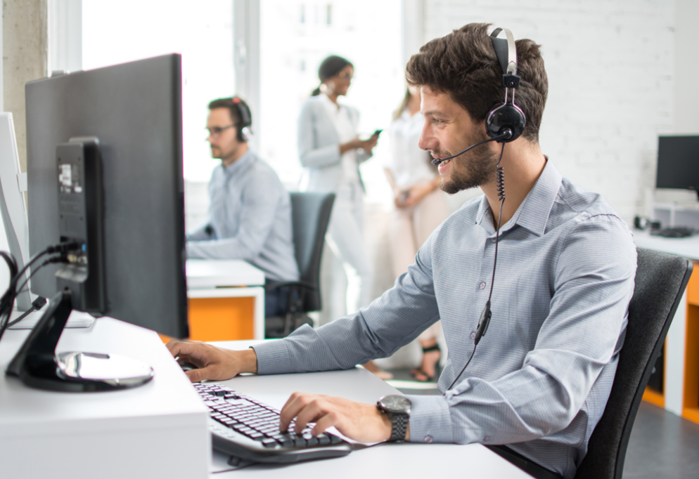 Visuel d'un homme à l'ordinateur portant un casque d'écoute fournissant une assistance à la clientèle en arrière bureau.