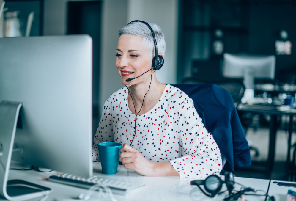 Visuel d'une femme à l'ordinateur, portant un casque d'écoute, fournissant une assistance à la clientèle en arrière bureau.