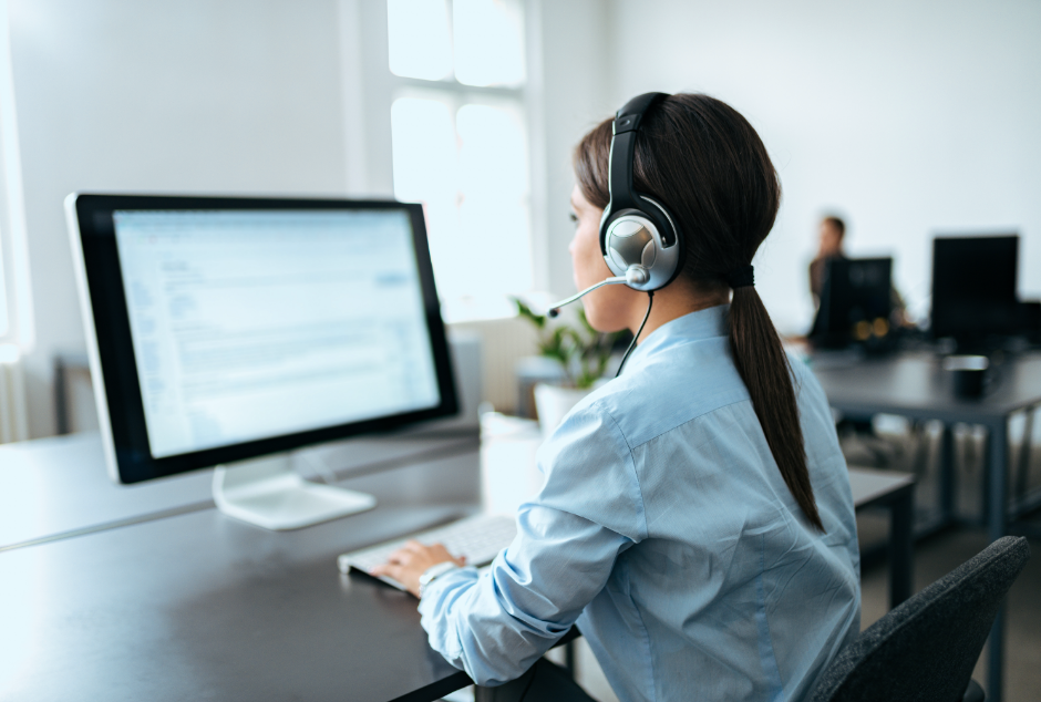 Photo of woman at a computer and wearing a headset providing customer service