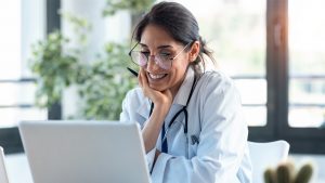 Médico supervisando el programa de apoyo al paciente desde un ordenador portátil.